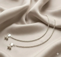 Indian payal silver and gold traditional anklet set featuring delicate bells on a soft fabric.